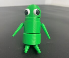 Красочная 3D-печатная игрушка в форме зелёного робота с глазами